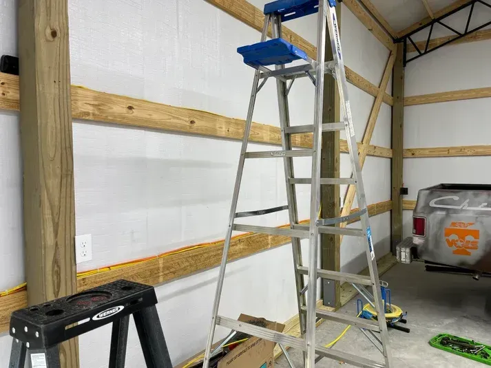 Ladder set up inside a barn, next to a wooden beam wall.