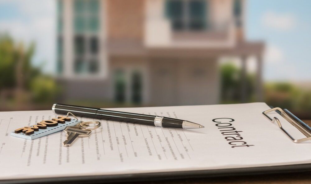 A Clipboard With a Pen and Keys on It in Front of a House — Key2 Conveyancing In Hallidays Point, NSW