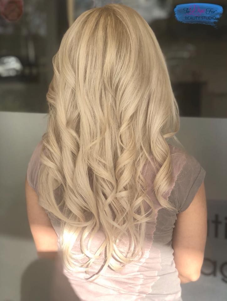 A woman with long blonde hair is sitting in front of a window.