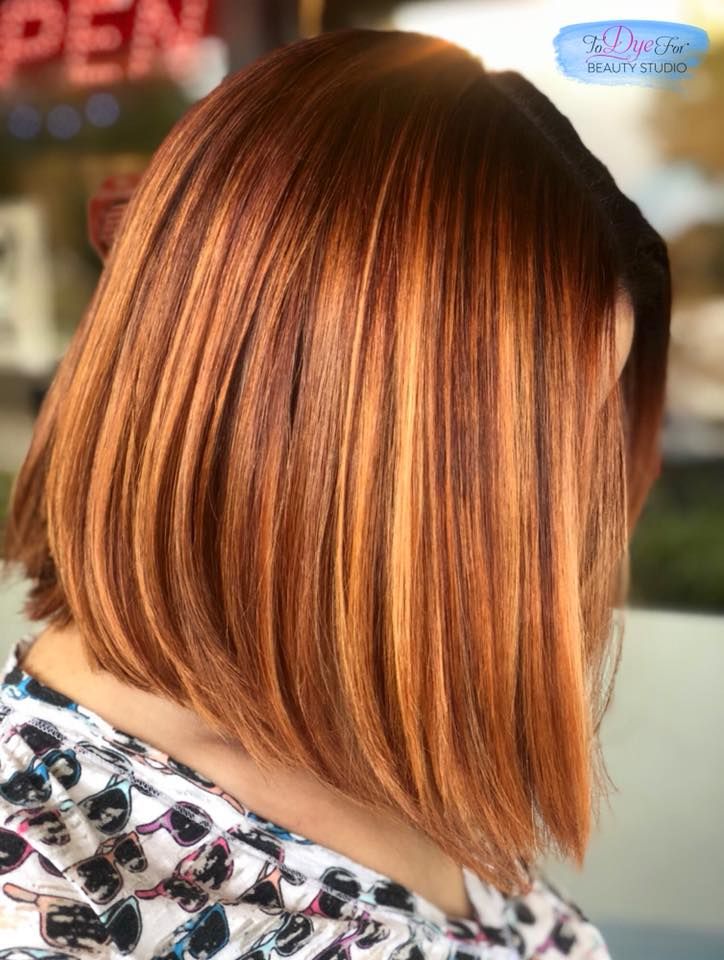 A woman with long brown hair is wearing a floral shirt.