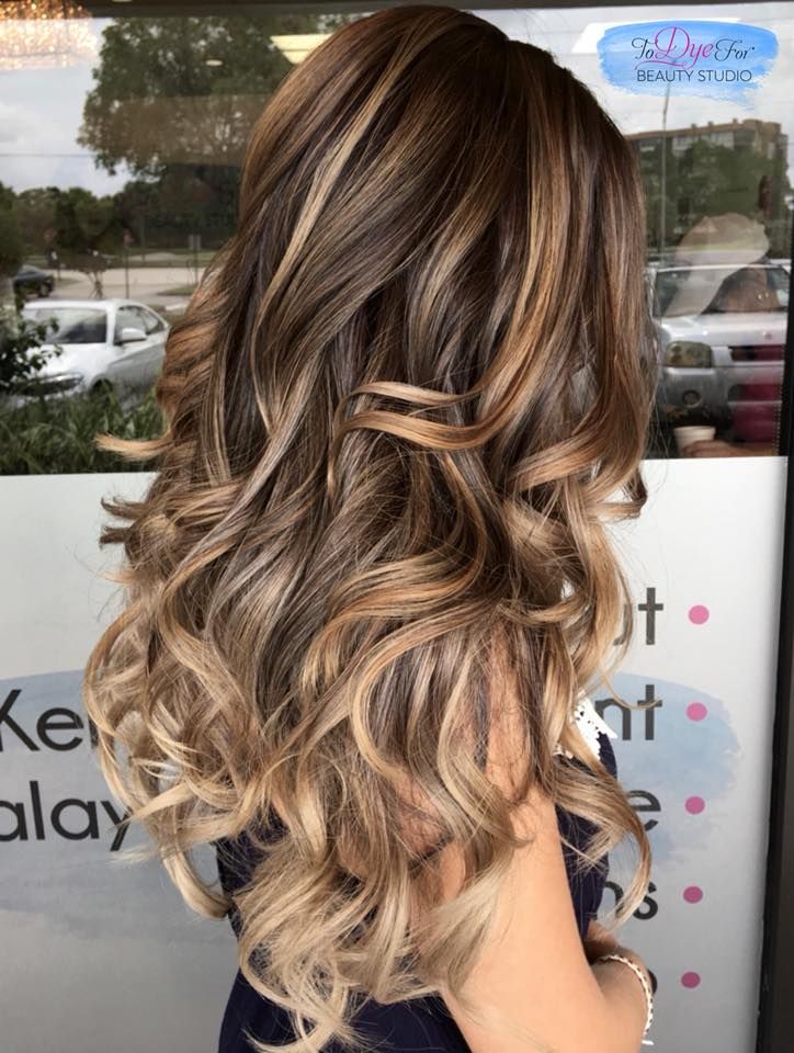 A woman with long brown hair is standing in front of a window.