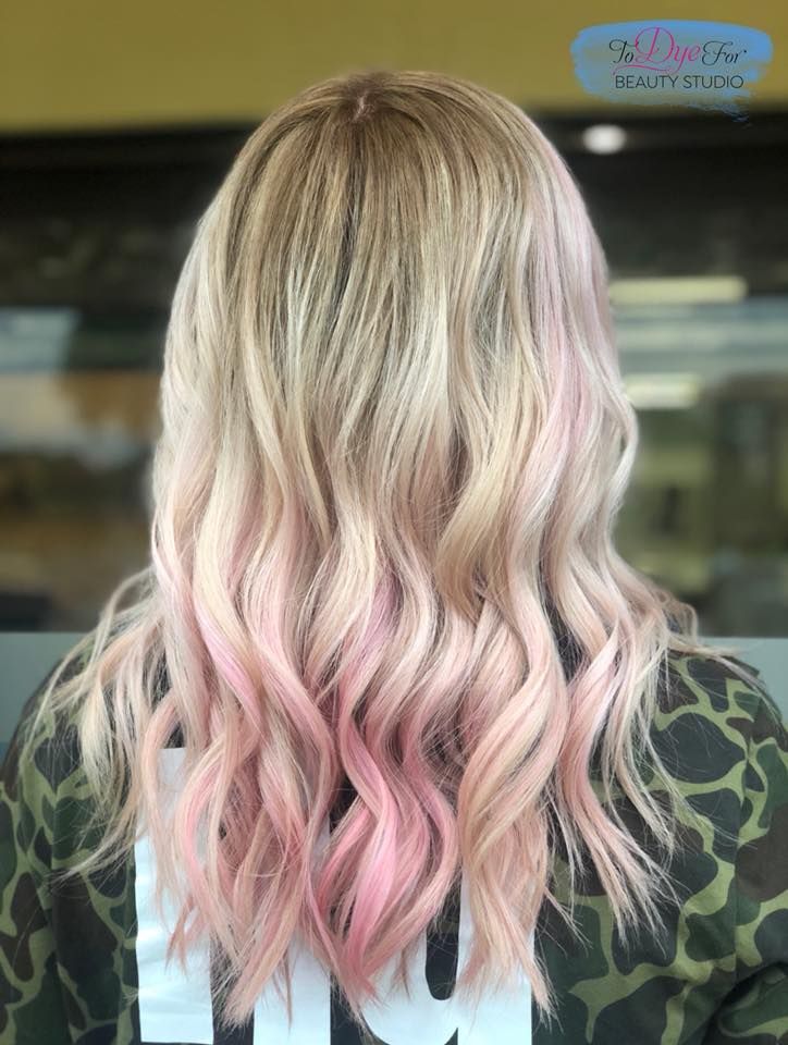 A woman with blonde and pink hair is wearing a camouflage shirt.