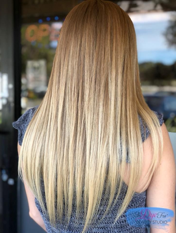 A woman with long blonde hair is standing in front of a window.
