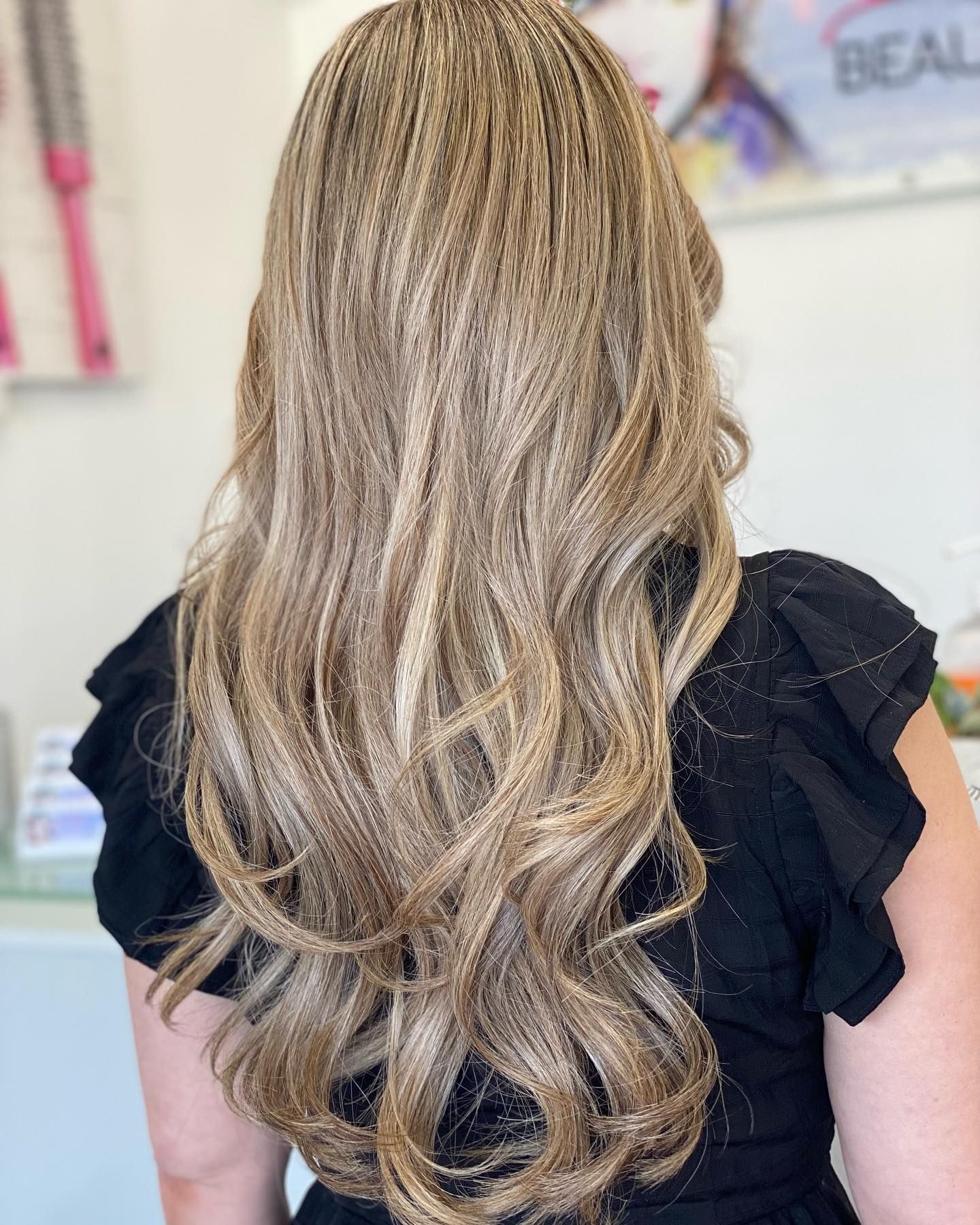 A woman with long blonde hair is wearing a black dress