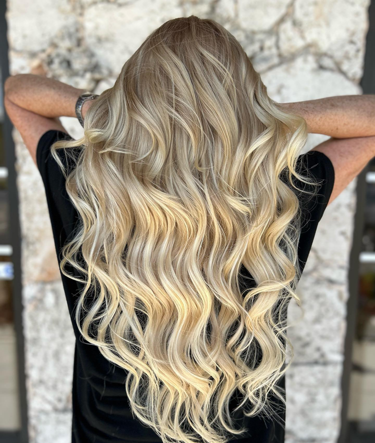 A woman with long blonde hair is wearing a black shirt.