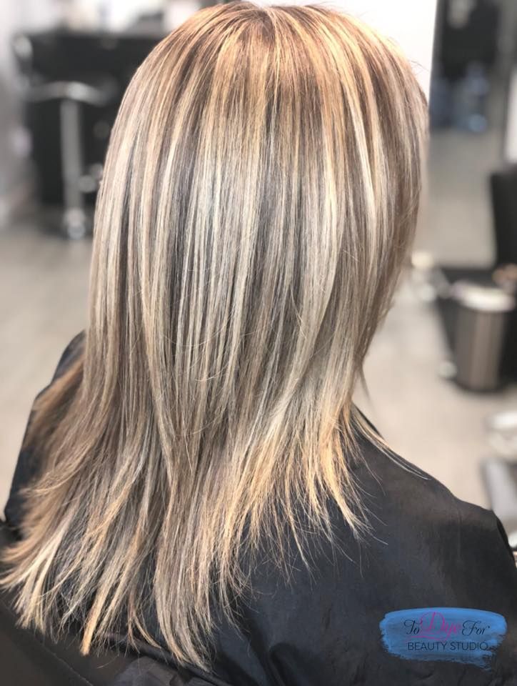 A woman with long blonde hair is sitting in a chair in a salon.