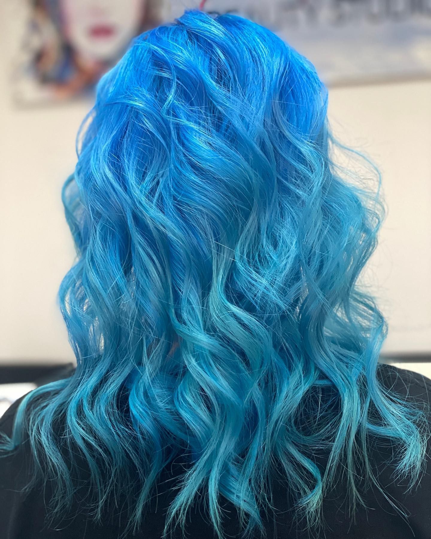 A woman with blue hair is wearing a black shirt.