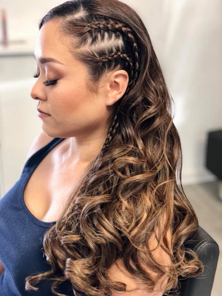 A woman with long curly hair is wearing a braided hairstyle.