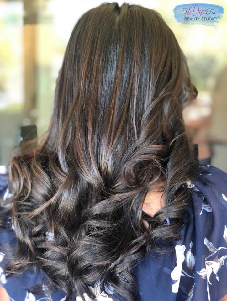 A woman with long dark hair is wearing a blue floral shirt.