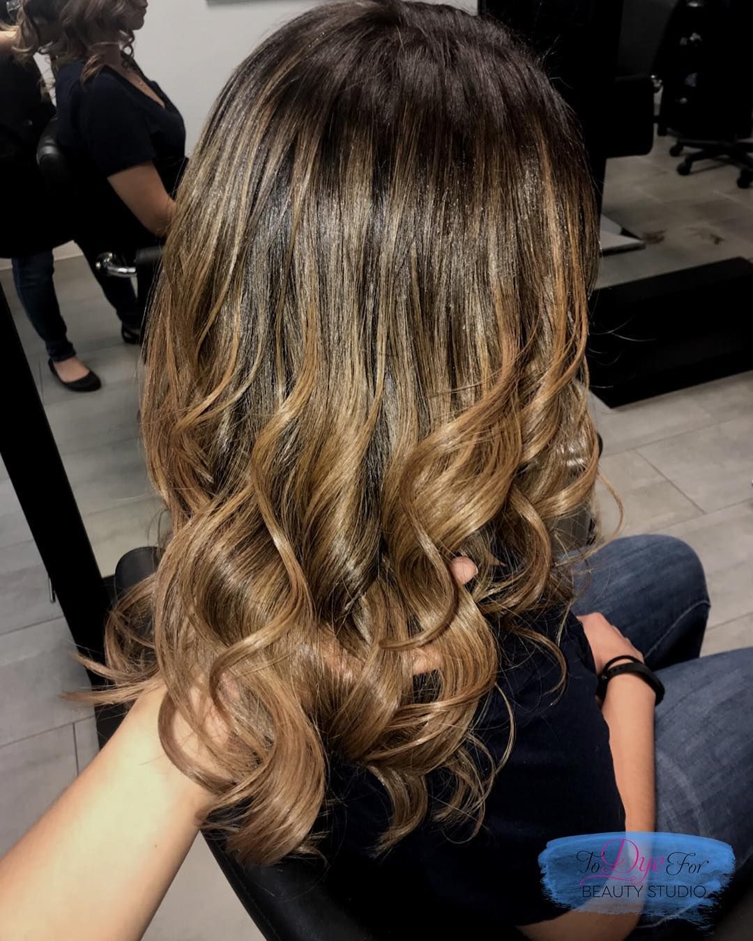 A woman with long brown hair is sitting in a chair