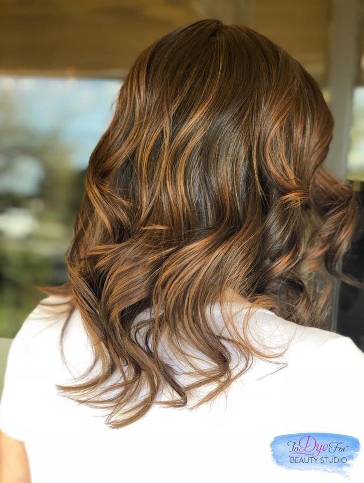 A woman with long brown hair is wearing a white shirt.