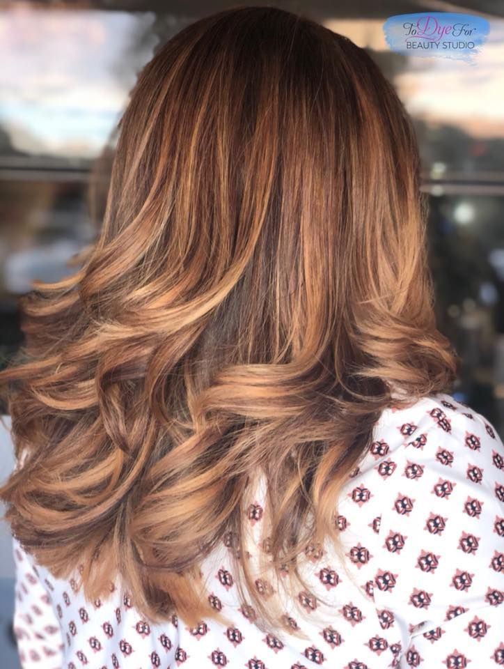 A woman with long brown hair is wearing a white polka dot shirt.