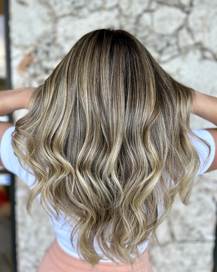 A woman with long blonde hair is wearing a white shirt and pink shorts.