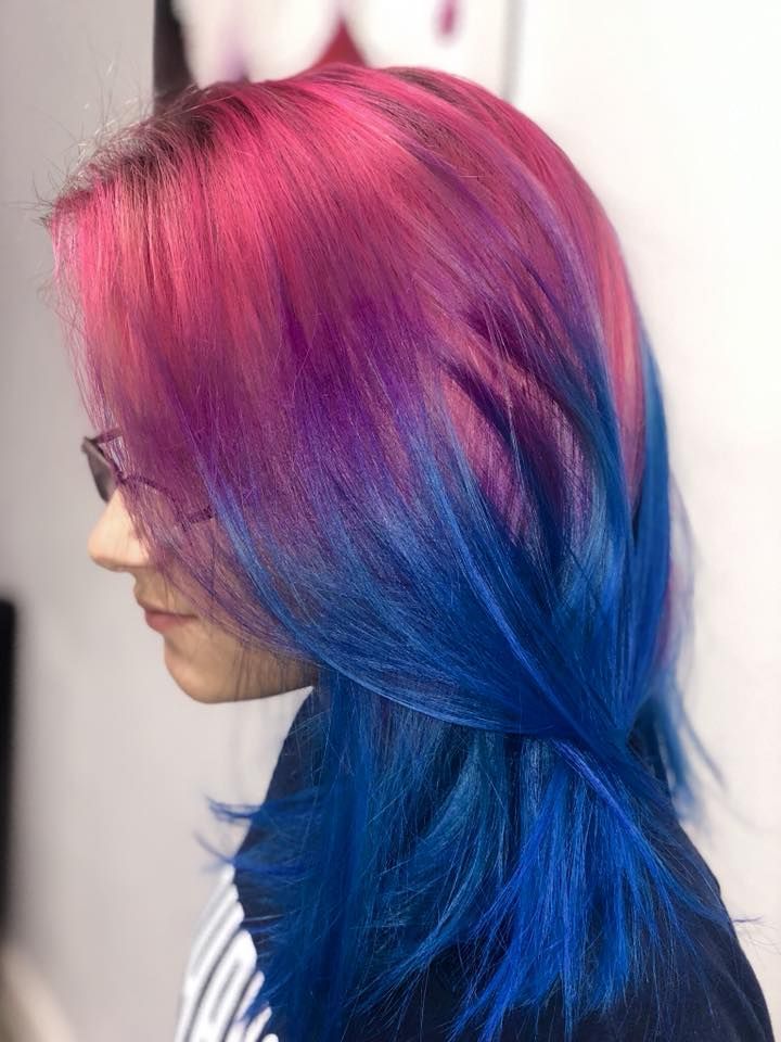 A woman with pink and blue hair is wearing glasses.