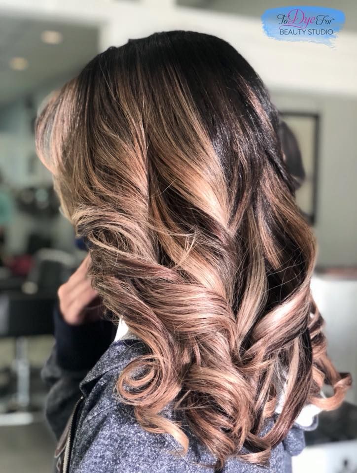A woman with long brown hair is standing in a salon.