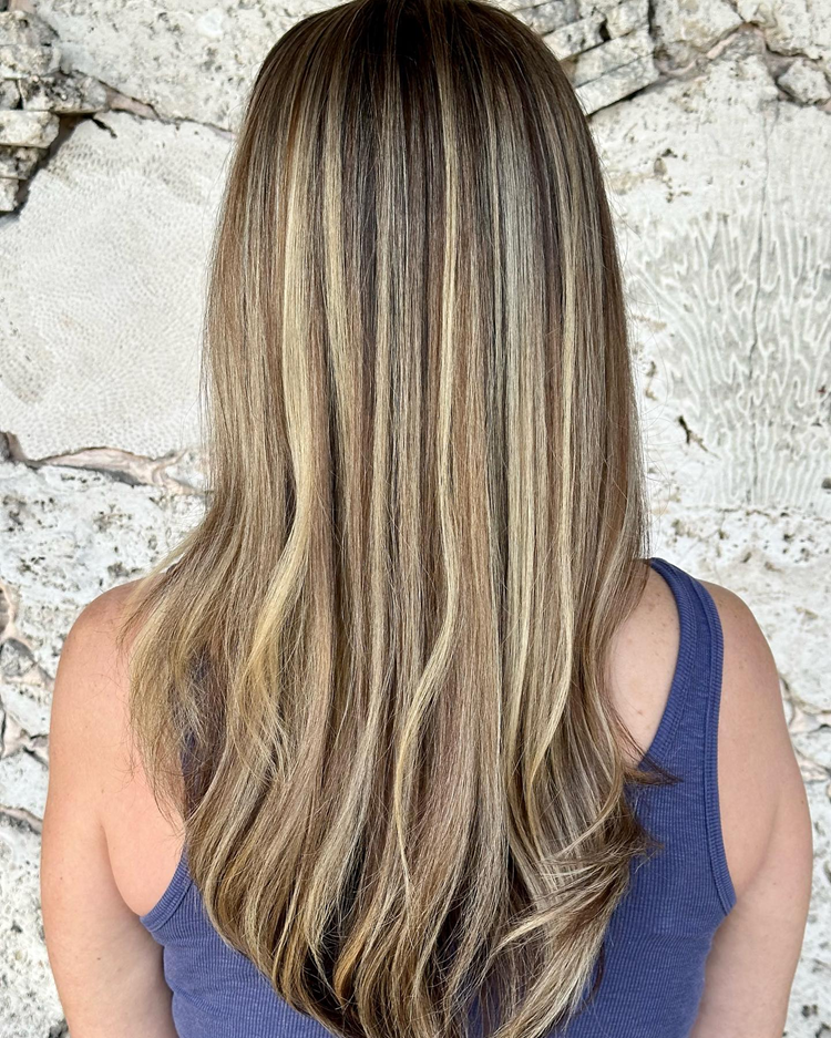 A woman with long blonde hair is wearing a blue tank top.