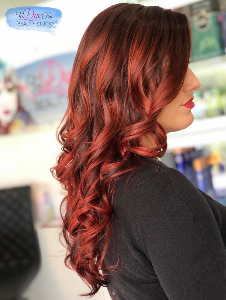 A woman with long red hair is wearing a black shirt
