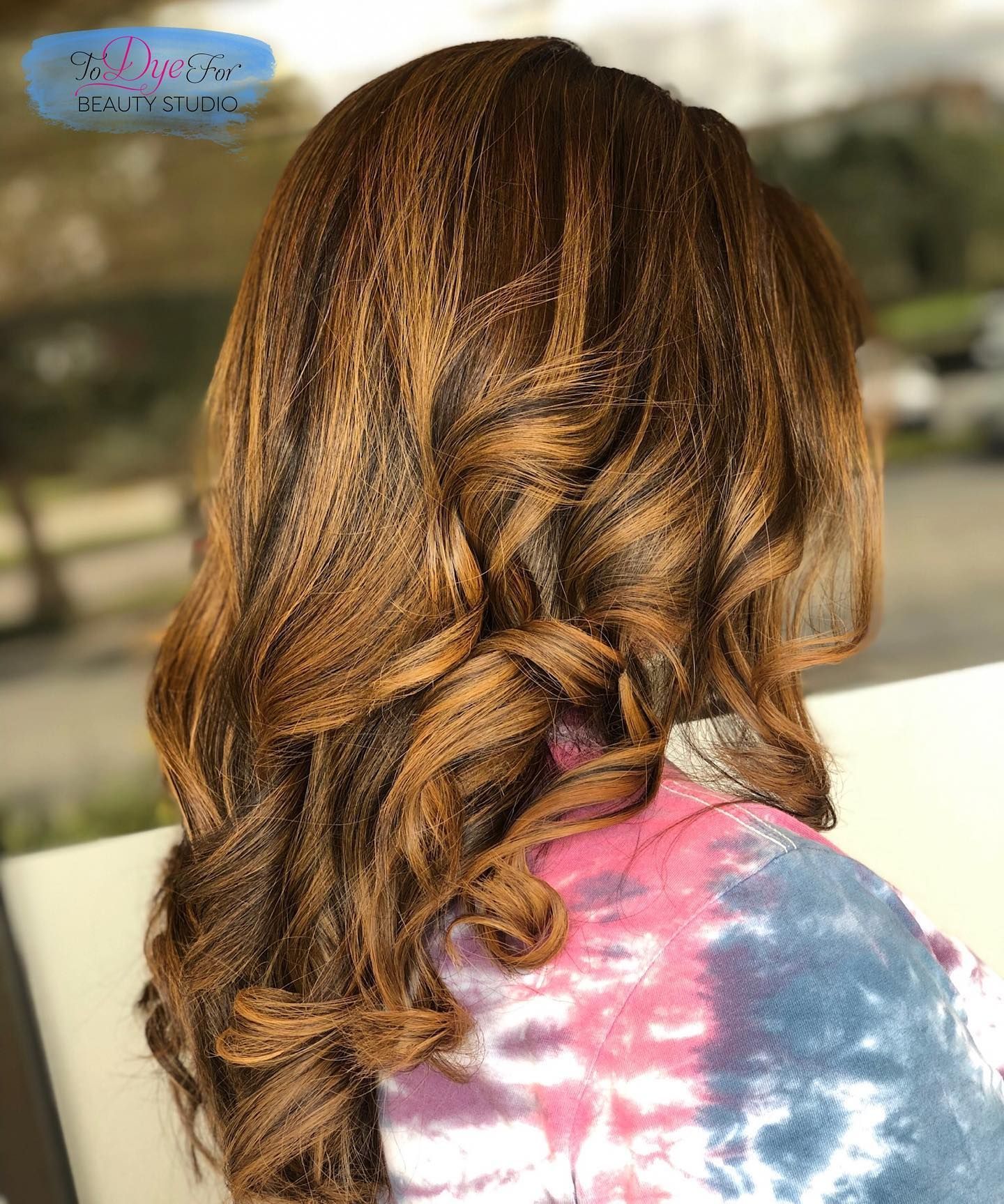 A woman with long brown hair is wearing a tie dye shirt.
