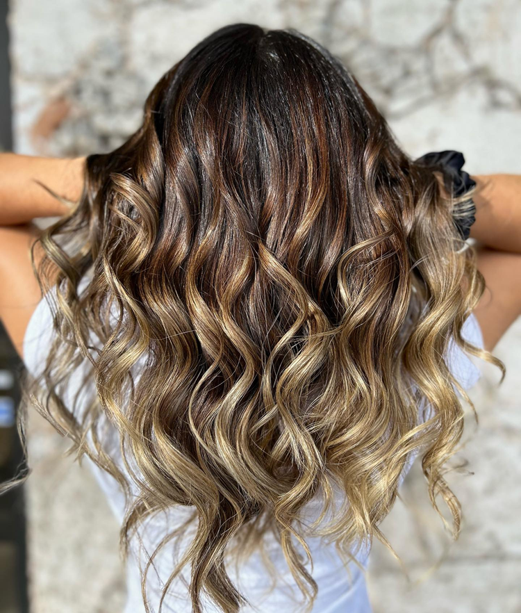 A woman with long curly hair is wearing a white shirt.