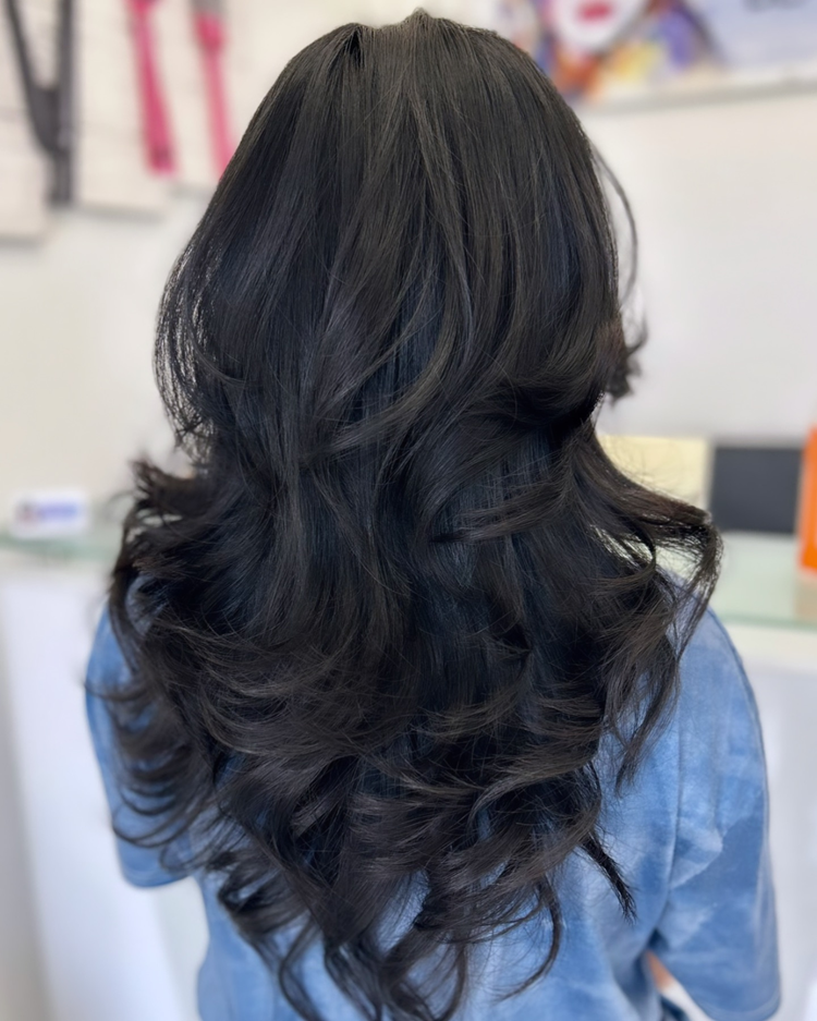 A woman with long black hair is wearing a blue shirt.