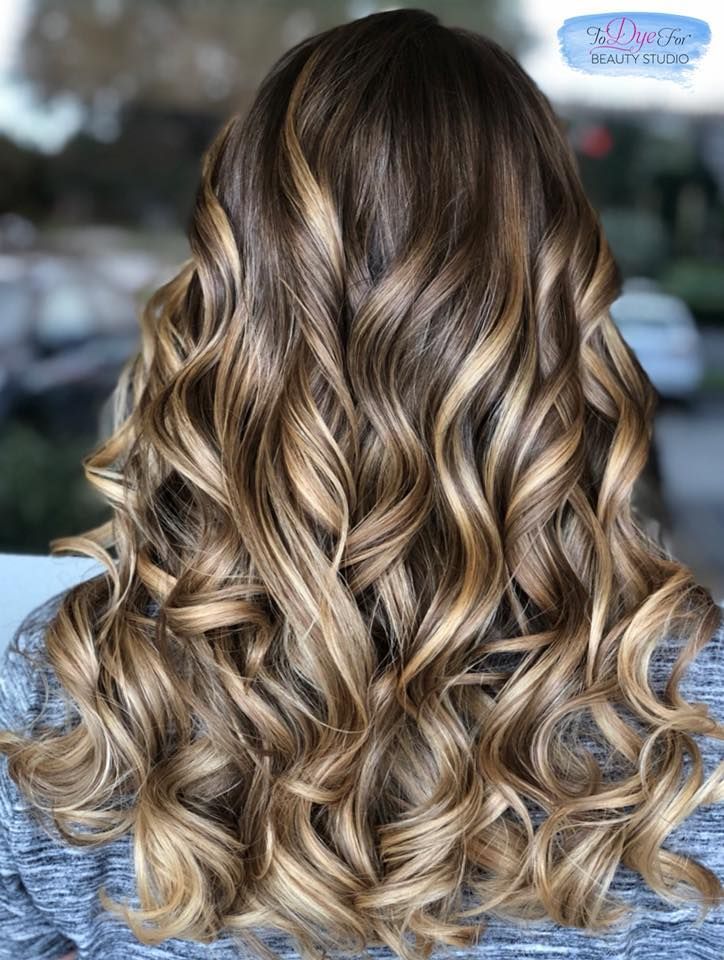 The back of a woman 's head with long curly hair.