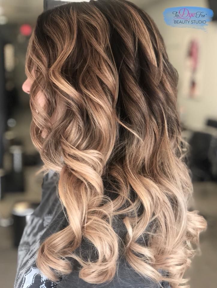 A woman with long wavy hair is standing in a salon.