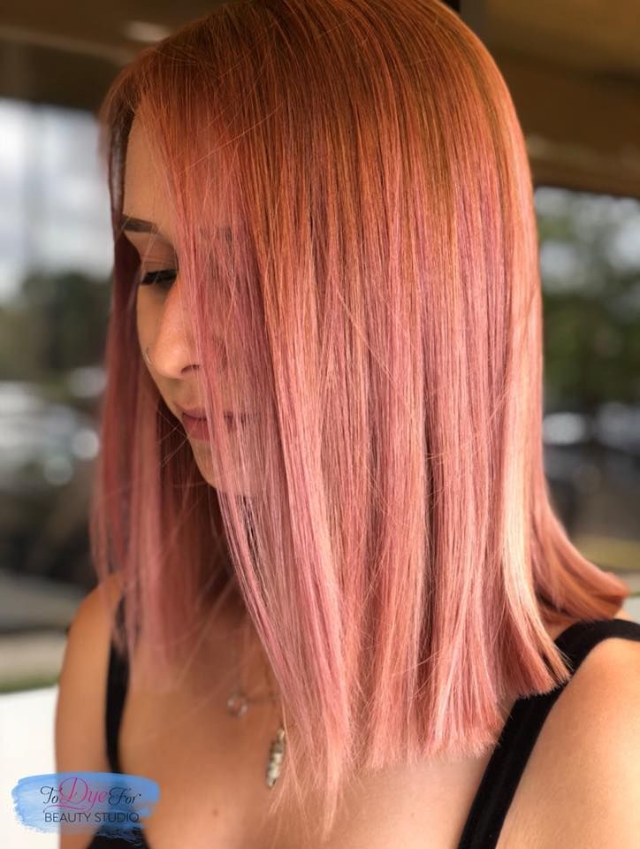 A woman with pink hair is wearing a black tank top and a necklace.