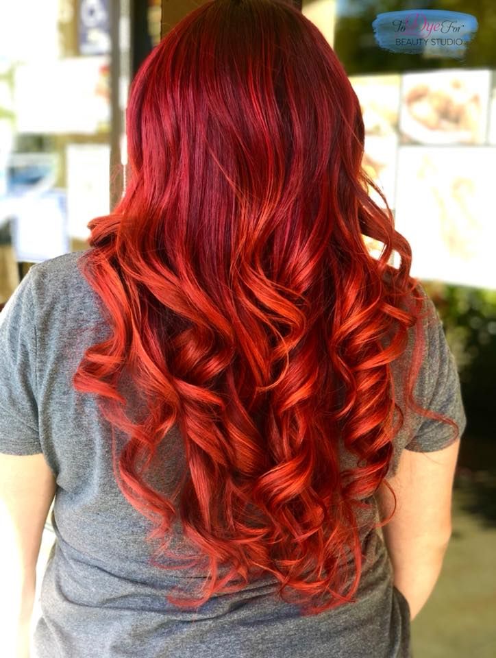 A woman with long red hair is wearing a gray shirt.