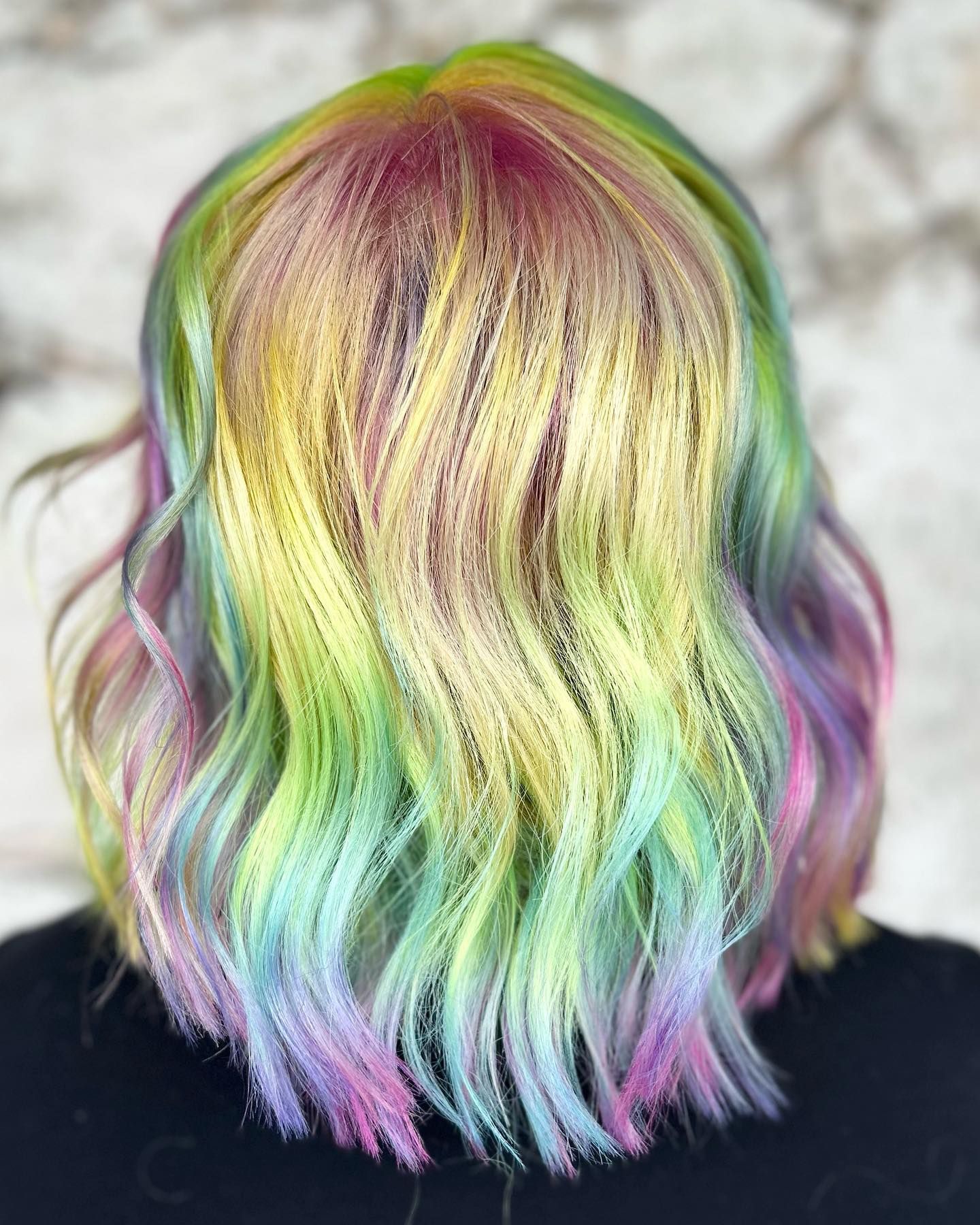 A woman with rainbow hair is wearing a black shirt.