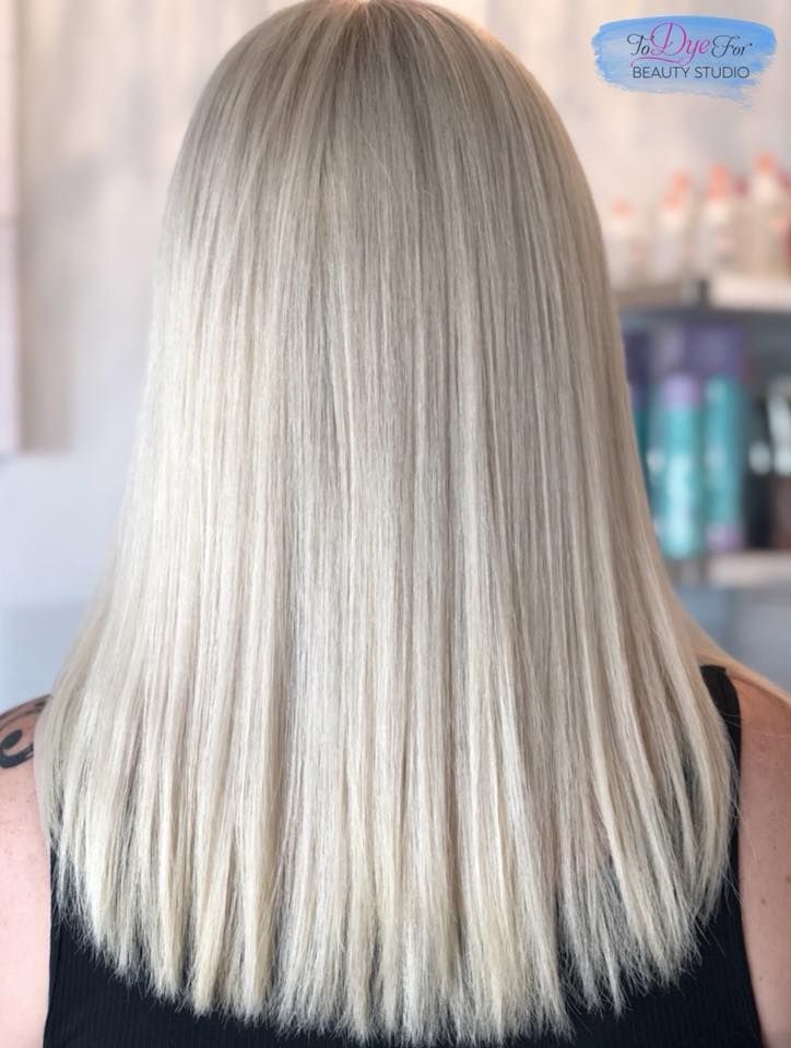 A woman with long blonde hair is wearing a black tank top.