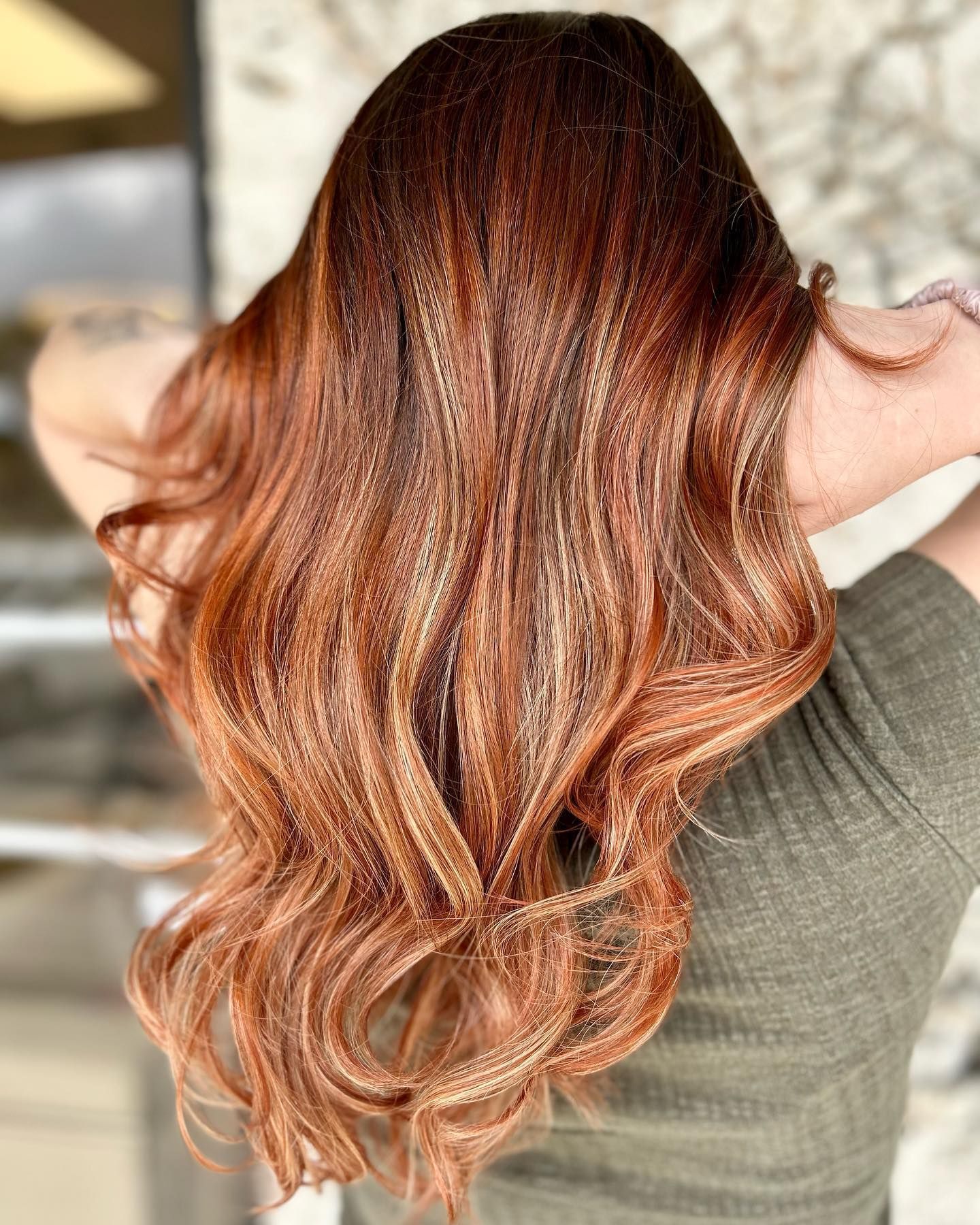 A woman with long red hair is wearing a green shirt.