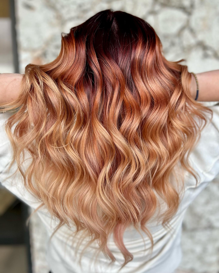The back of a woman 's head with long wavy red and blonde hair.