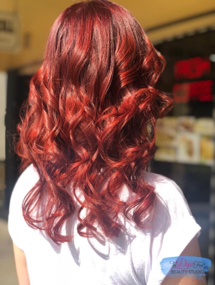 A woman with long red hair is wearing a white shirt.