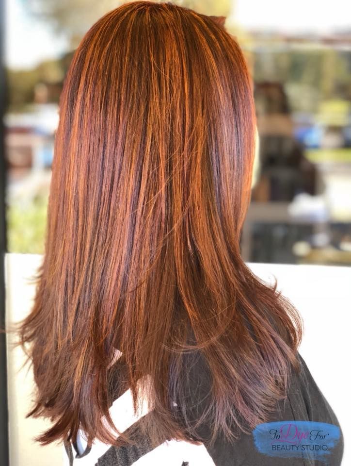 A woman with long red hair is standing in front of a window.
