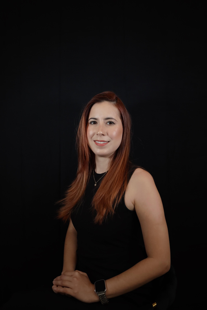 A woman with red hair is posing for a picture in front of a black background.