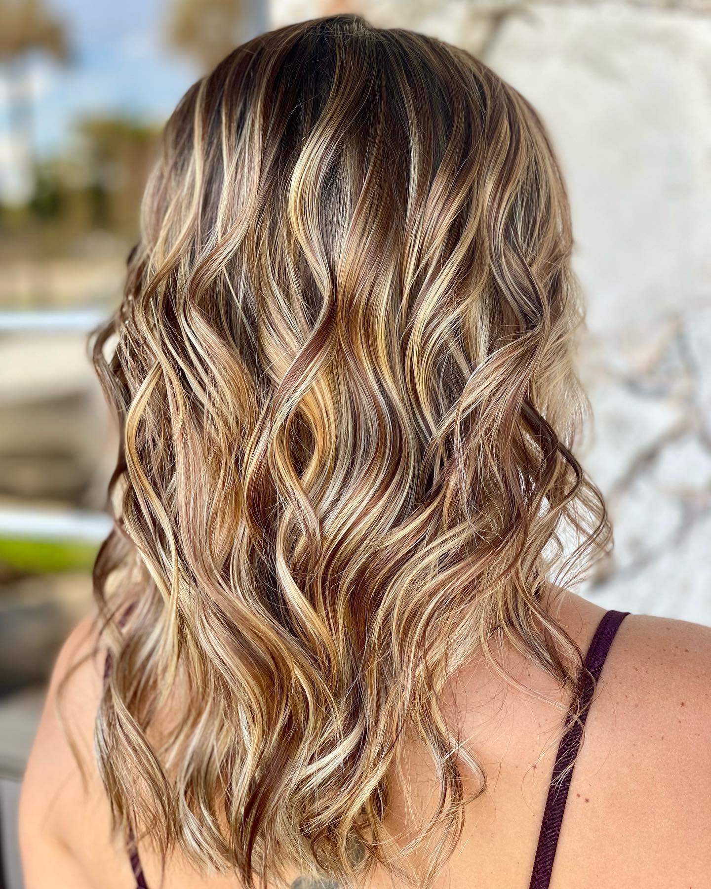 A woman with long wavy hair is wearing a purple tank top.