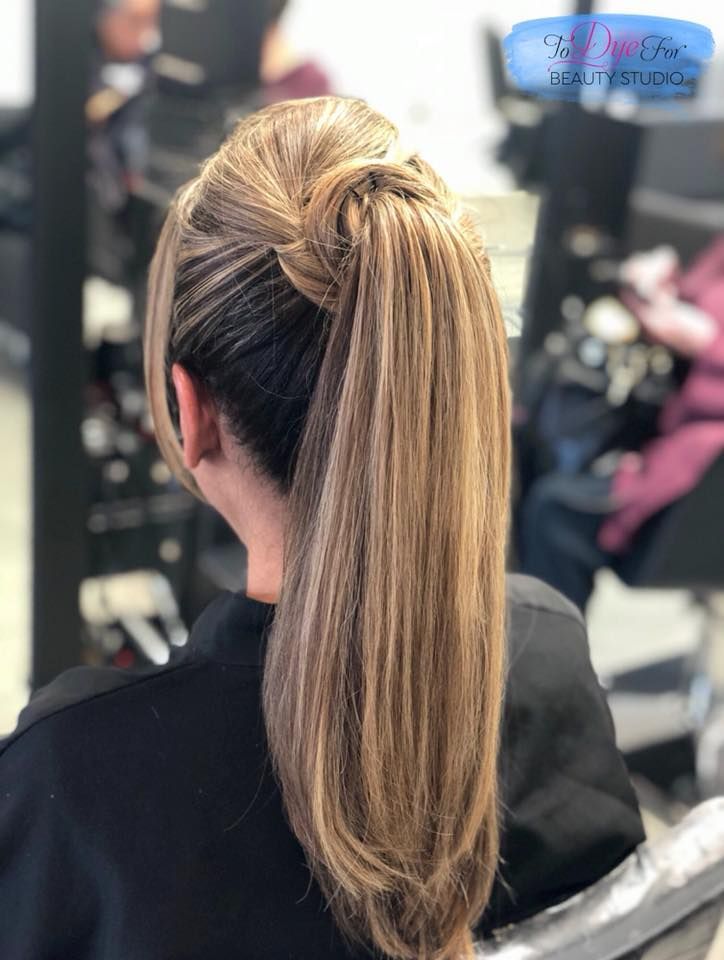A woman is sitting in a chair with her hair in a ponytail.