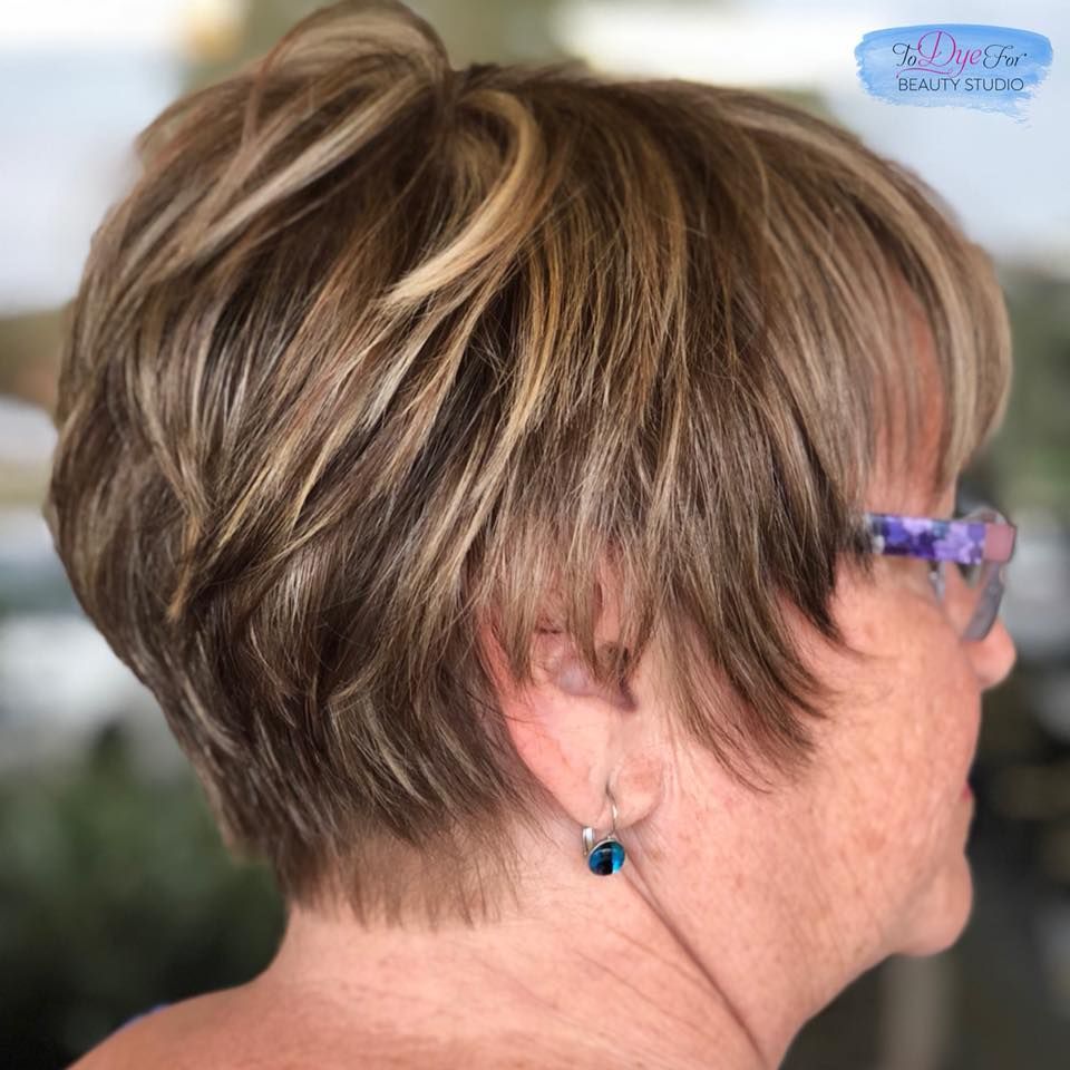 A woman wearing glasses and earrings has short hair