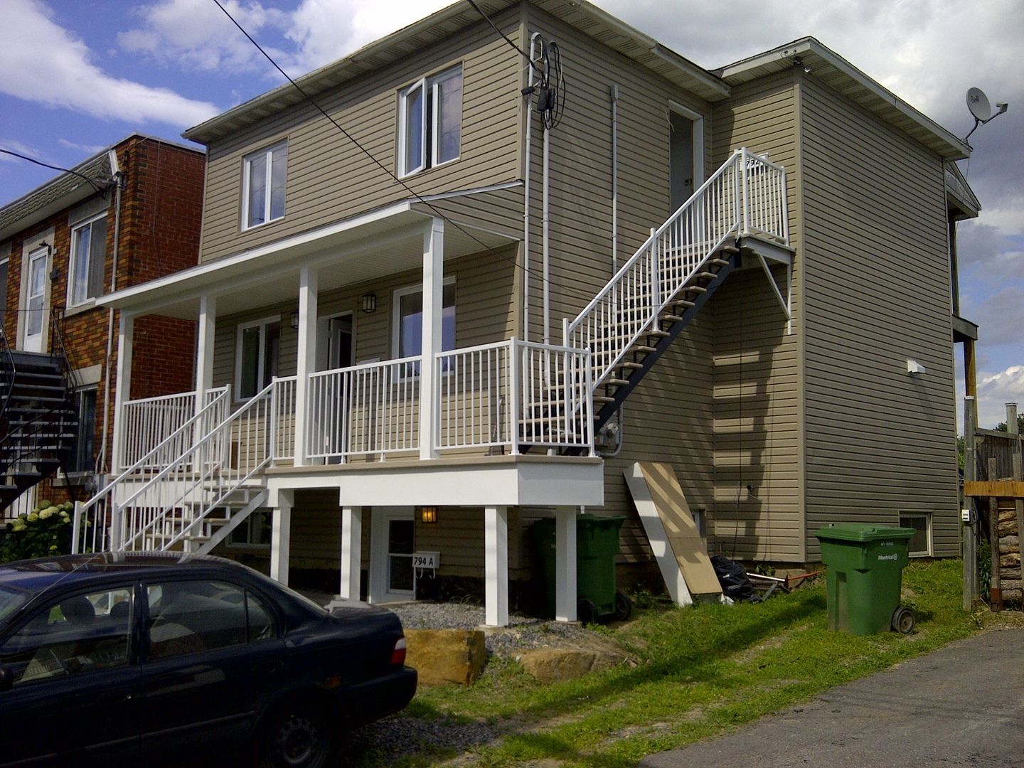 Une voiture est garée devant une maison avec des escaliers