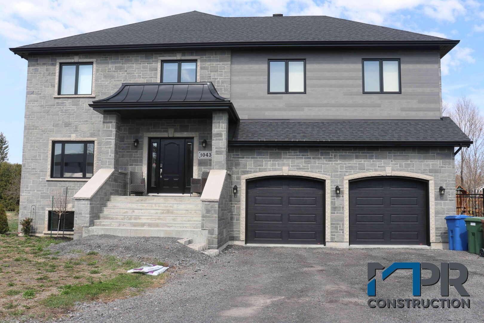 Une grande maison en brique avec trois portes de garage et des escaliers.