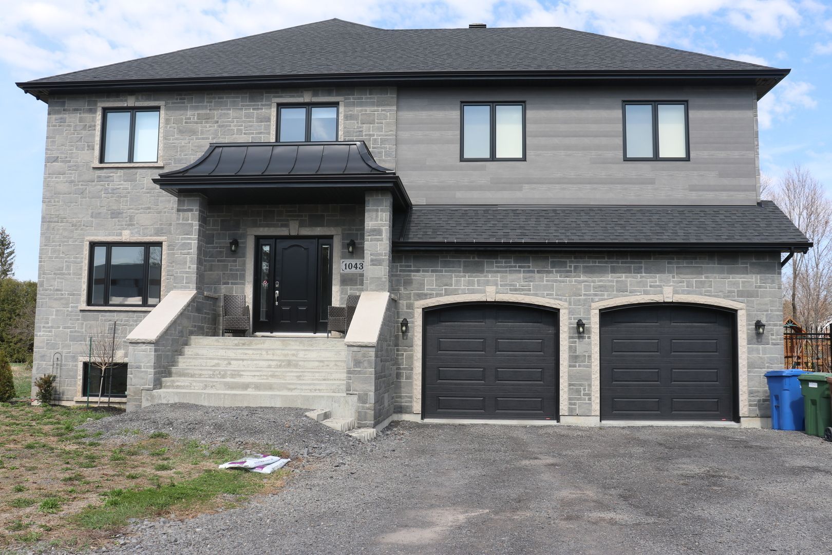 Une grande maison en brique avec trois portes de garage et des escaliers.