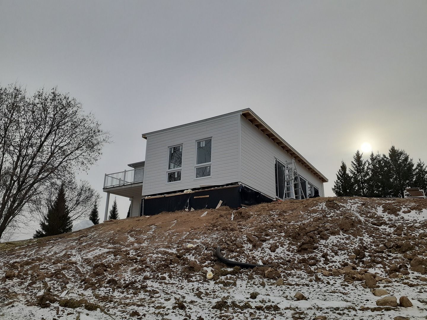 Une maison est assise au sommet d'une colline couverte de neige.