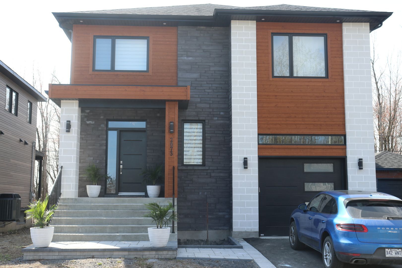 Une voiture bleue est garée devant une grande maison.