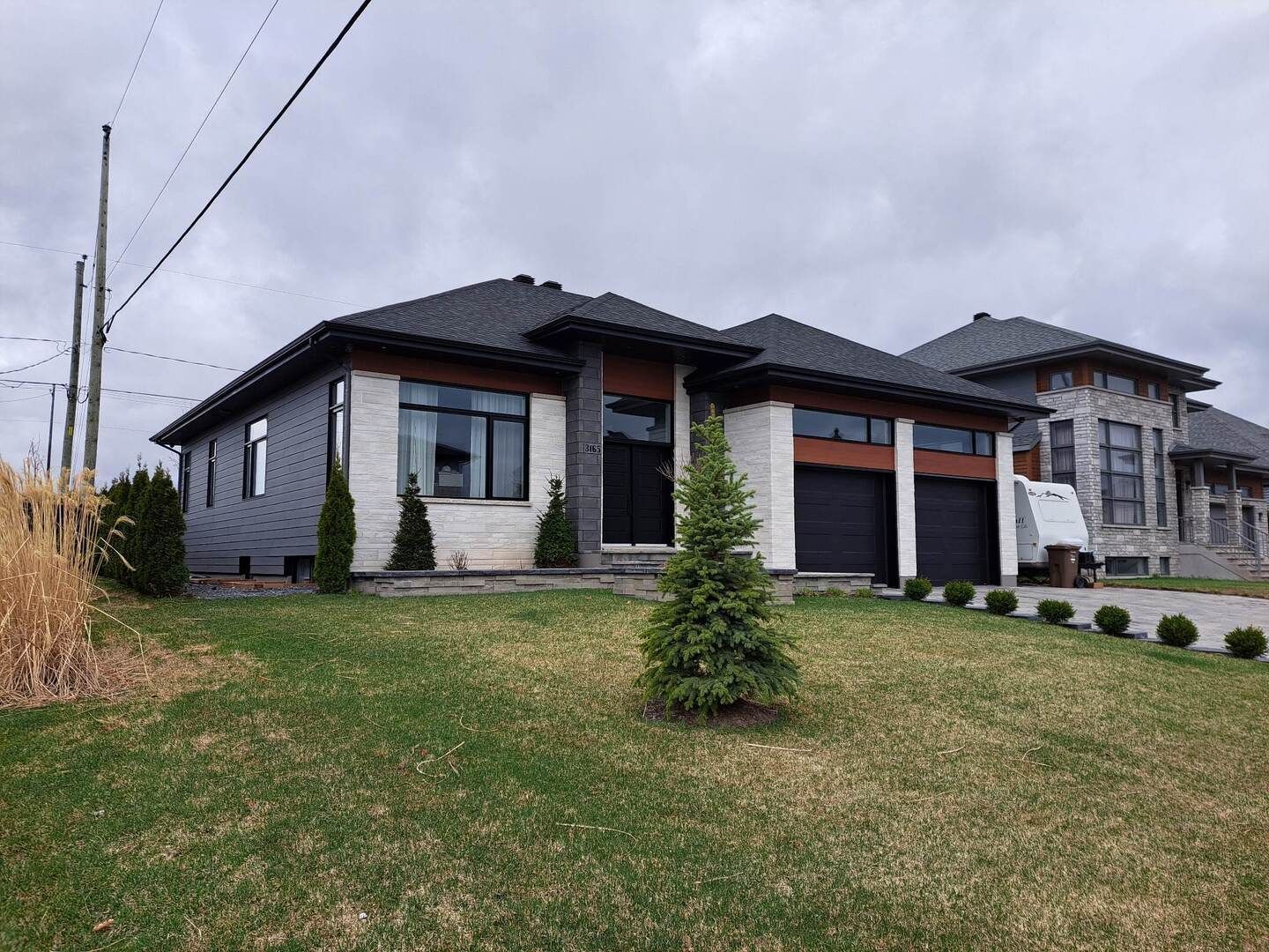 Une grande maison avec beaucoup de fenêtres est située au sommet d'une pelouse verte luxuriante.