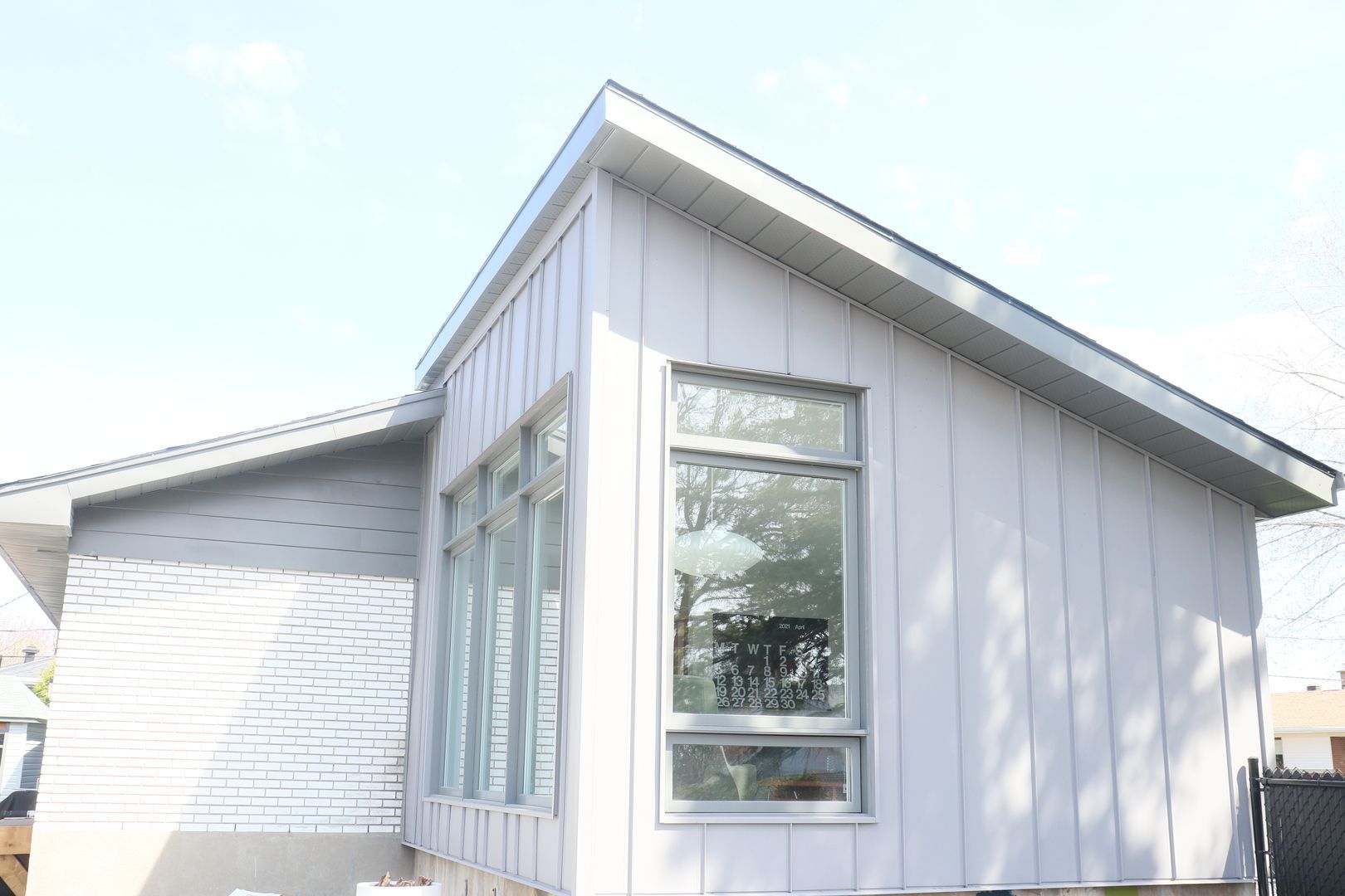 Une maison blanche avec un toit et beaucoup de fenêtres.