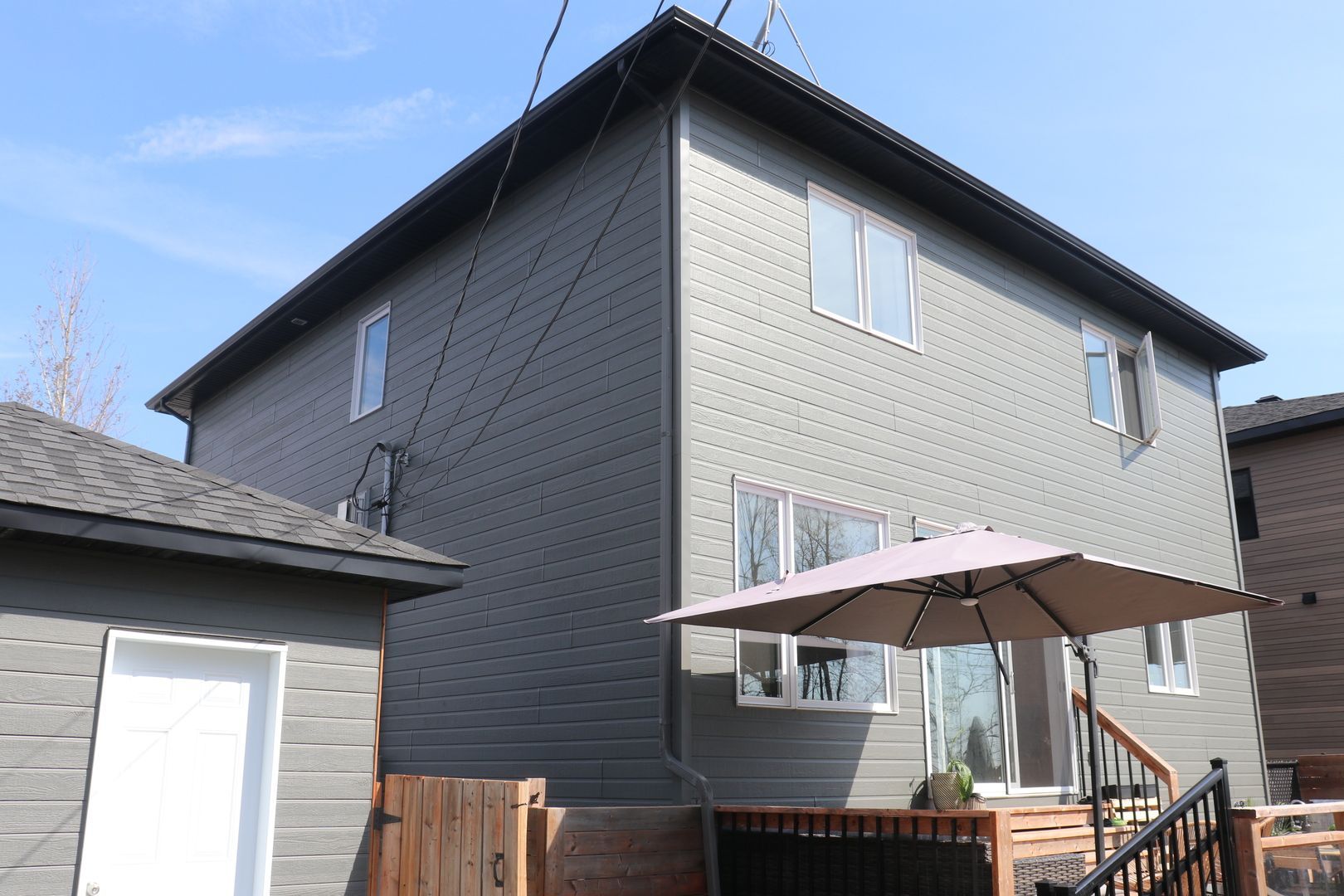 Une grande maison grise avec un parapluie rose devant.