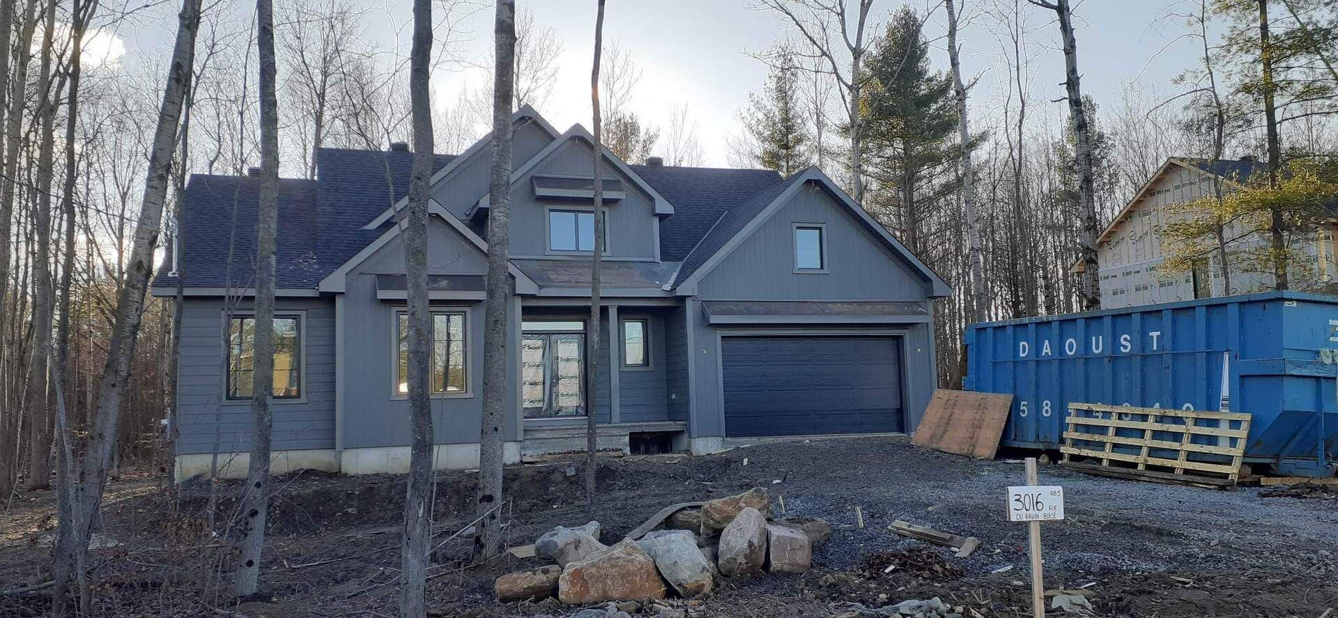 Une grande maison est en construction au milieu d'une forêt.