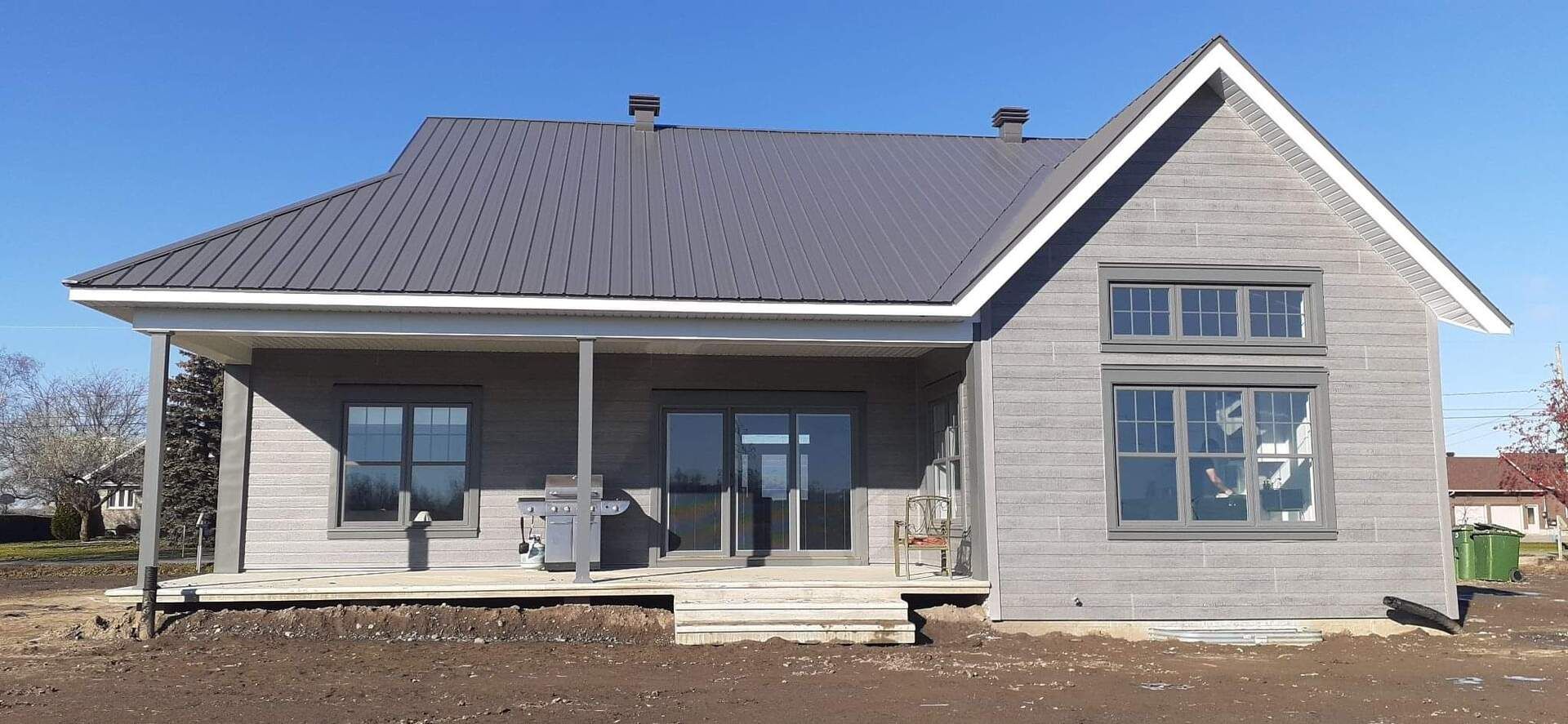 Une petite maison avec un toit en métal et un porche