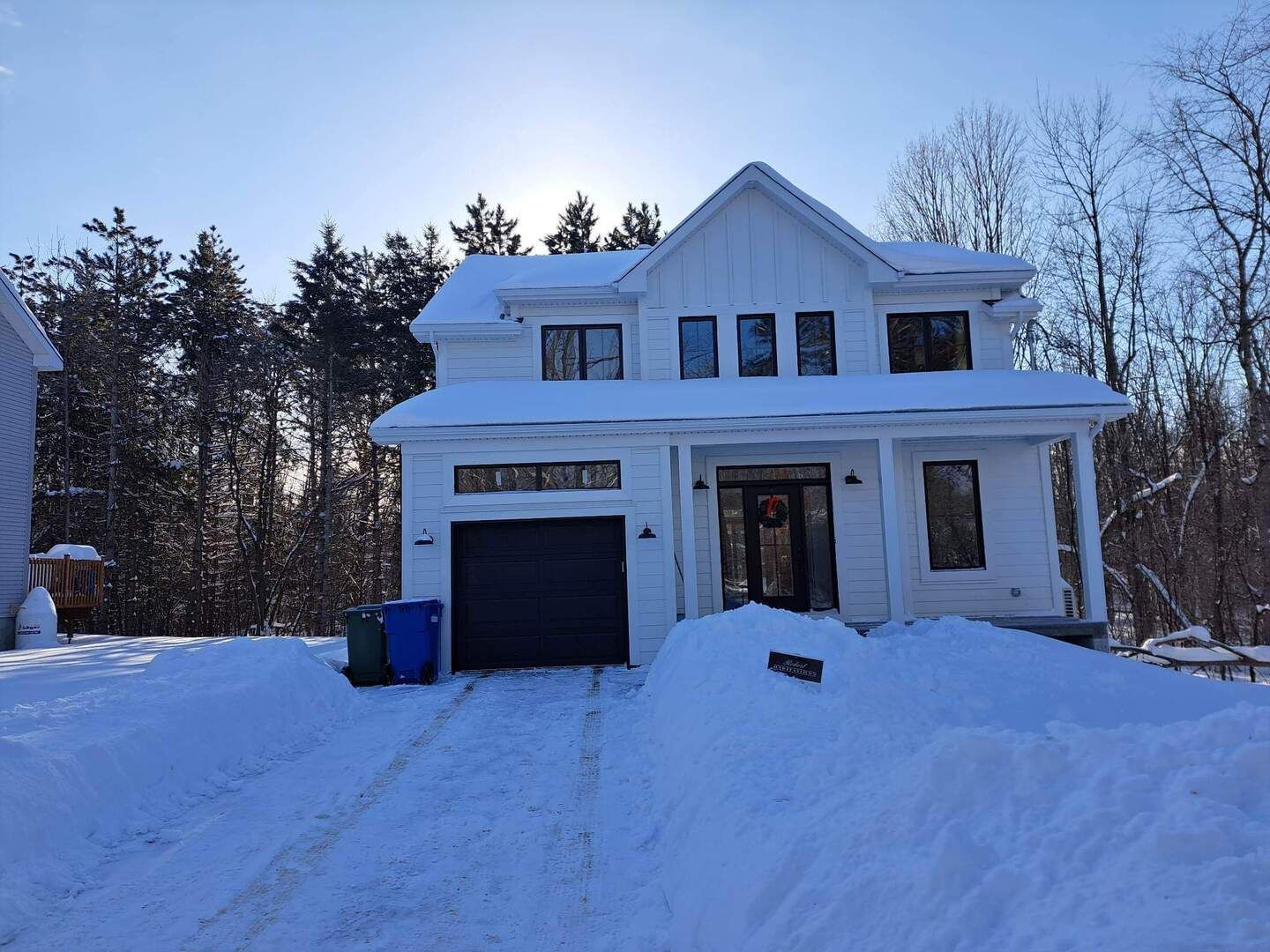 Une maison blanche avec un garage est recouverte de neige.