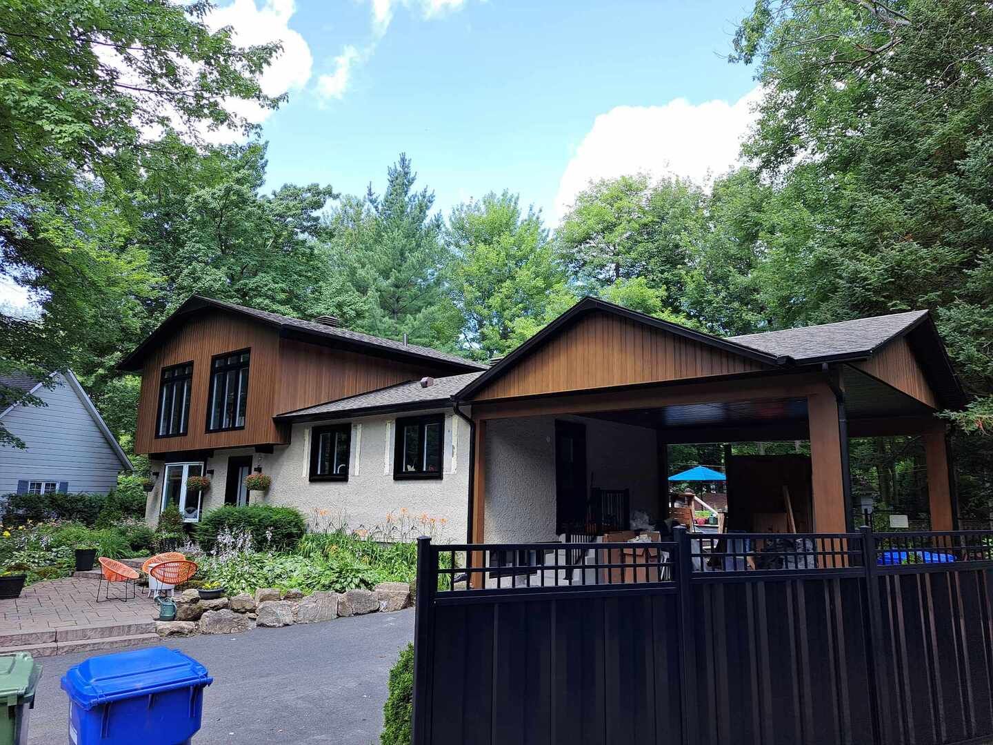 Une maison avec un toit en bois et un porche couvert est entourée d'arbres.